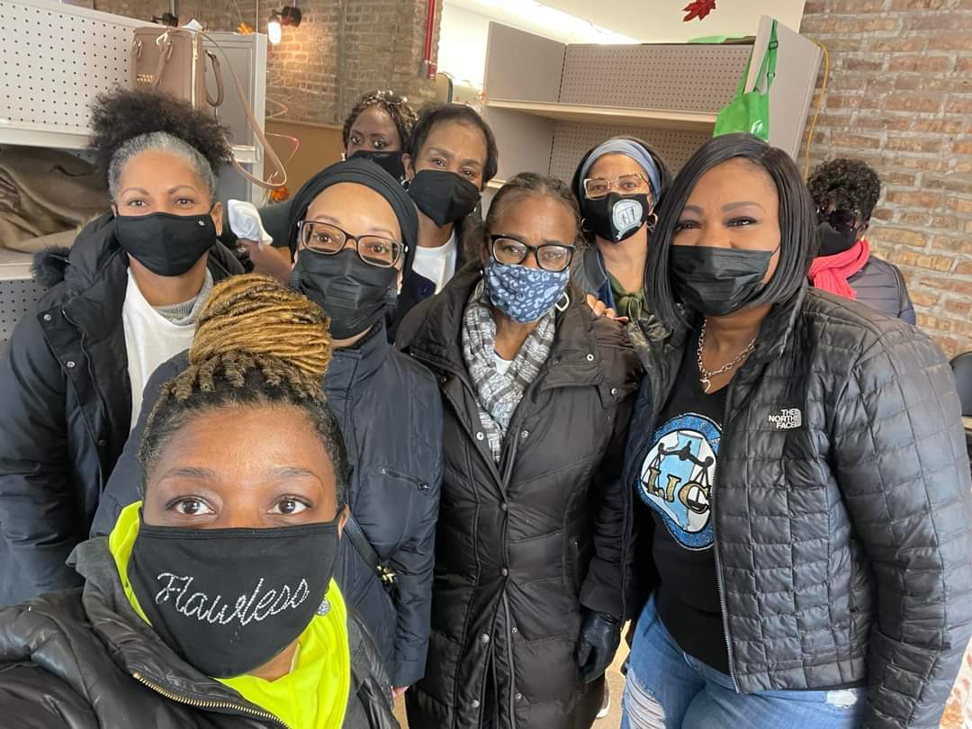 A group of masked women posing closely indoors.