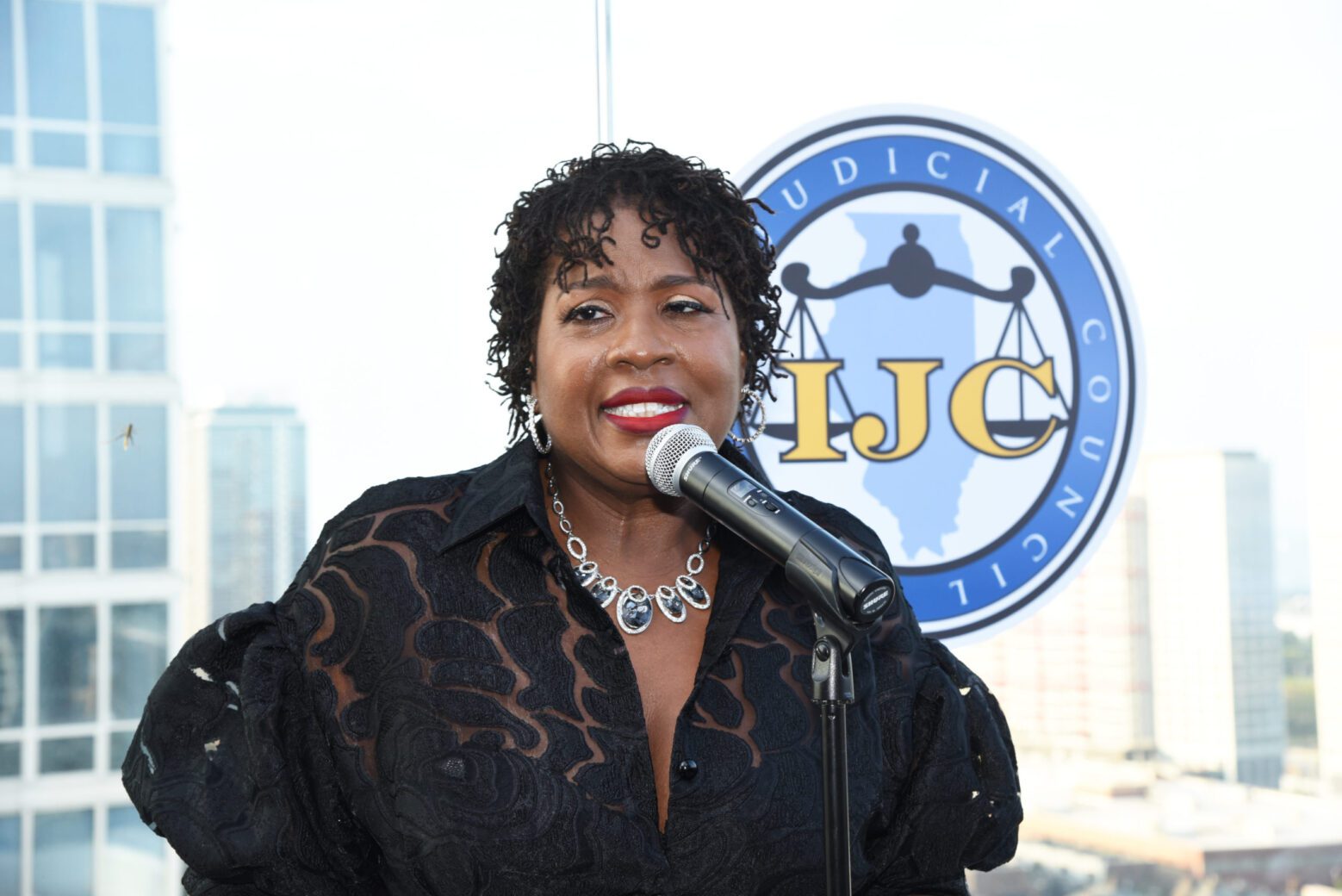 Woman speaking at a microphone in front of a logo.