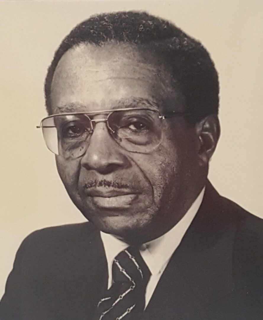 Portrait of an elderly man in glasses and a suit.