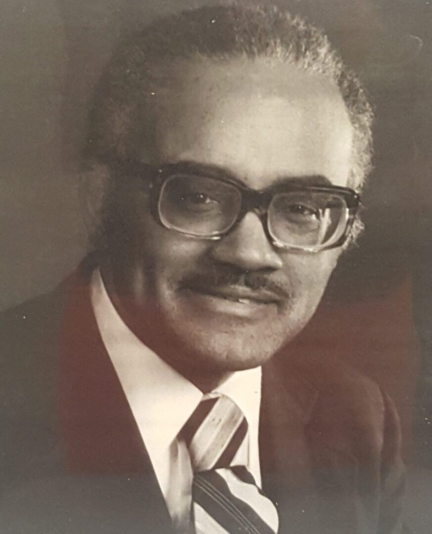 Black-and-white portrait of an older man with glasses and a mustache.