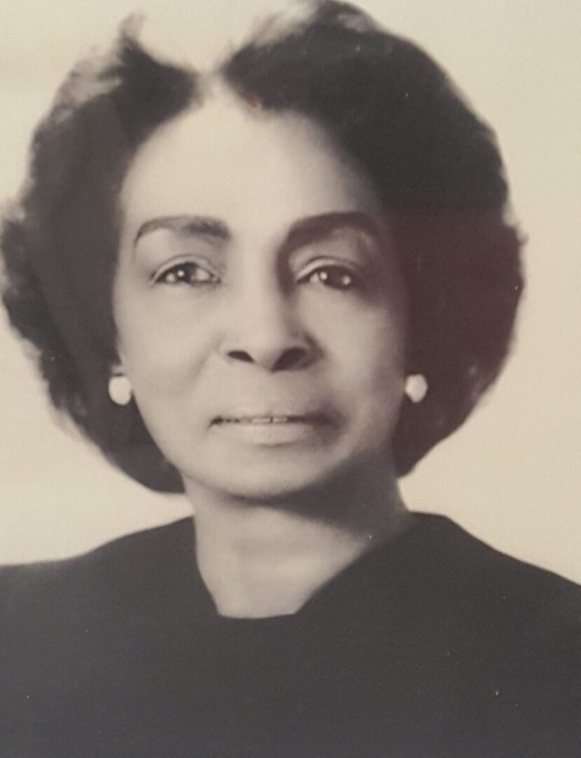 Black and white portrait of a dignified older woman with pearl earrings.