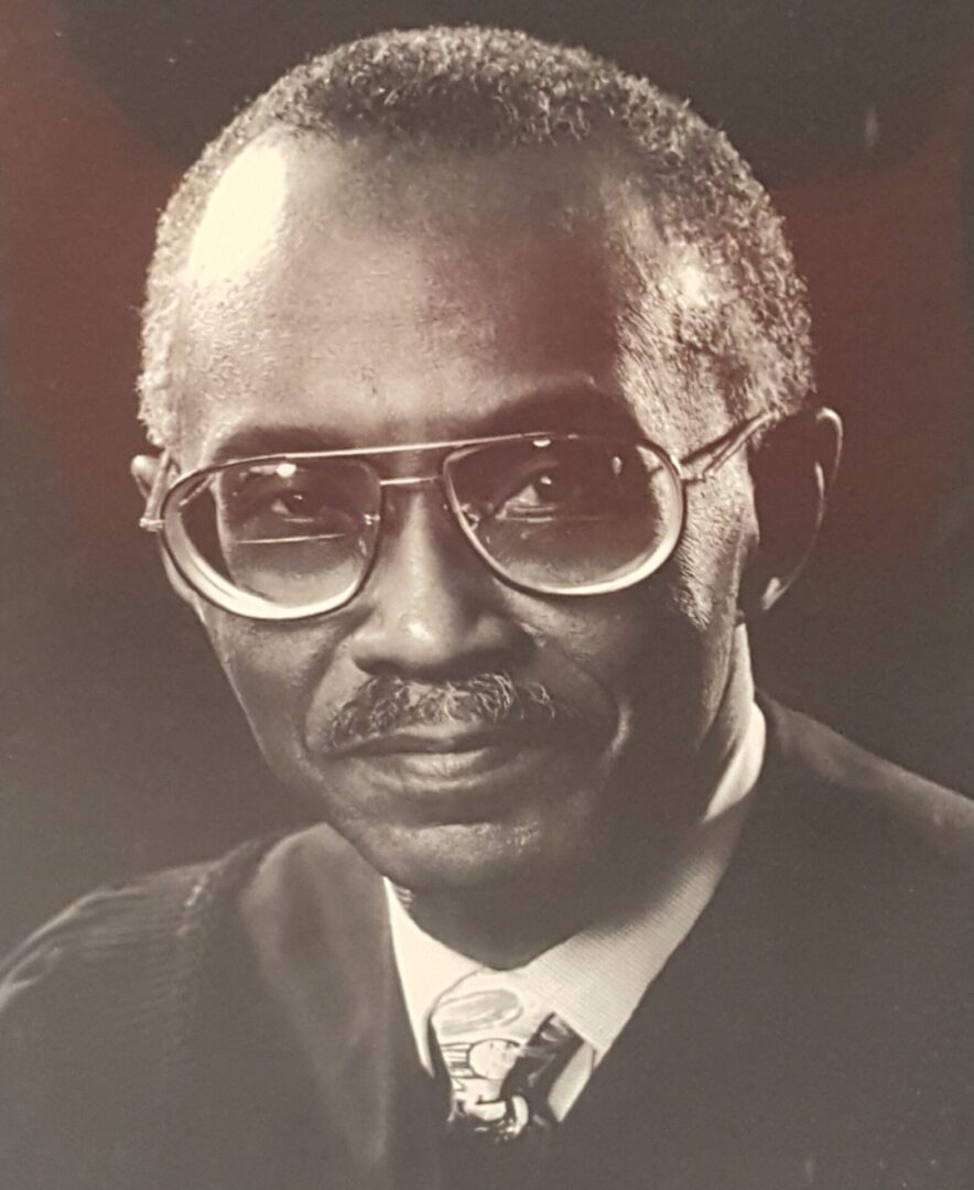 Portrait of an elderly man wearing glasses and a suit.