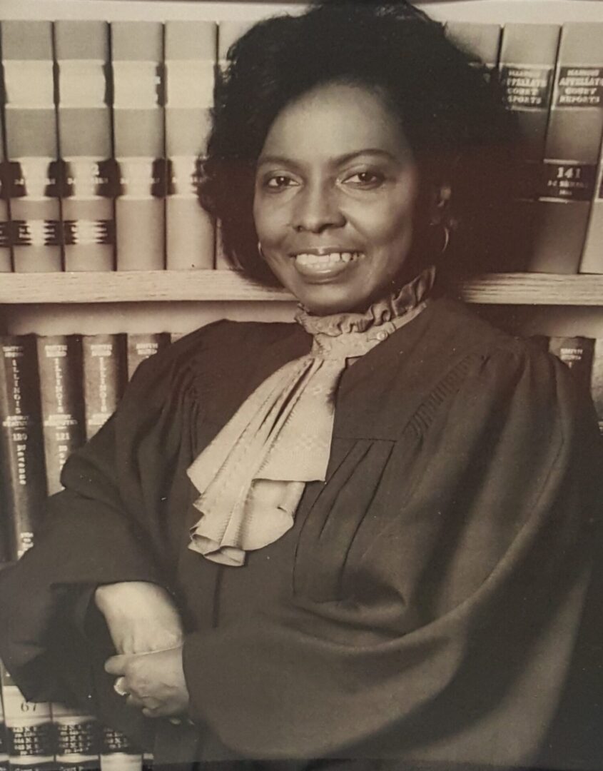 Black-and-white portrait of a woman in formal attire, smiling warmly.