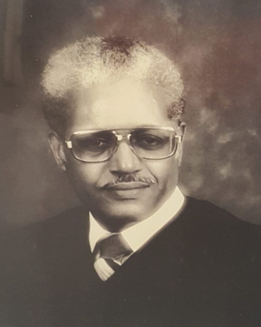 Black-and-white portrait of an older man with glasses and a mustache.