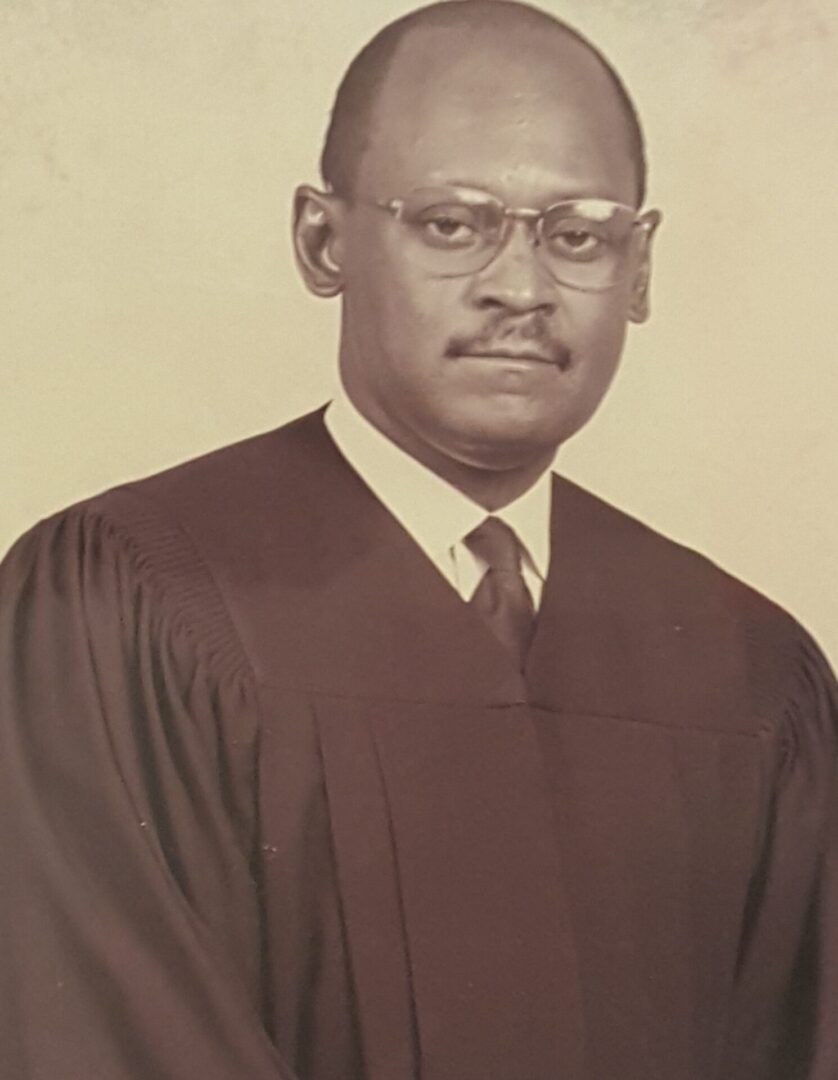 Portrait of a dignified man in judicial robes and glasses.