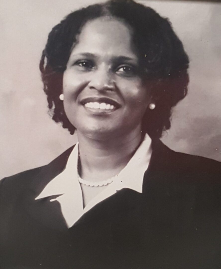 Black and white portrait of a smiling woman in formal attire.