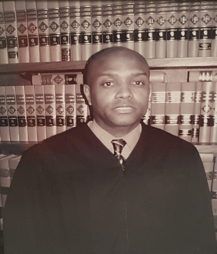 Portrait of a judge in robes in front of law books.