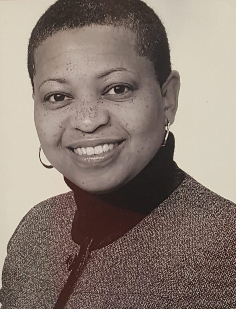 Smiling woman in a turtleneck and earrings.