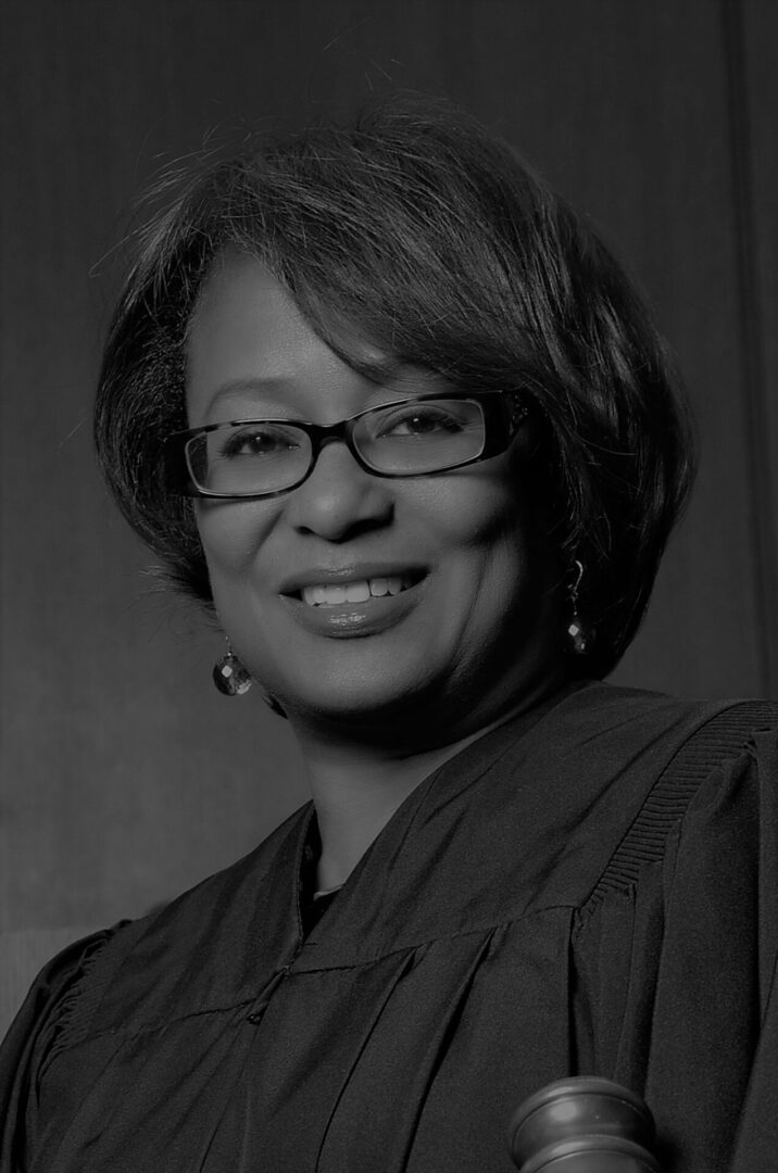 Black and white portrait of a smiling woman wearing glasses.