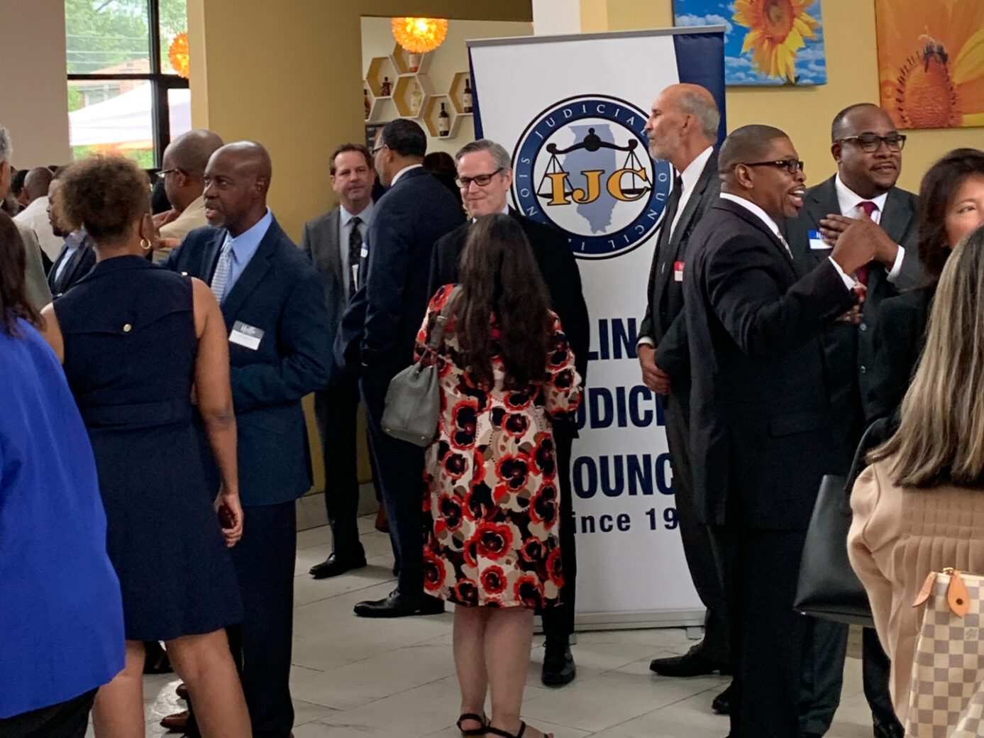 People mingling at a formal event with a banner in the background.