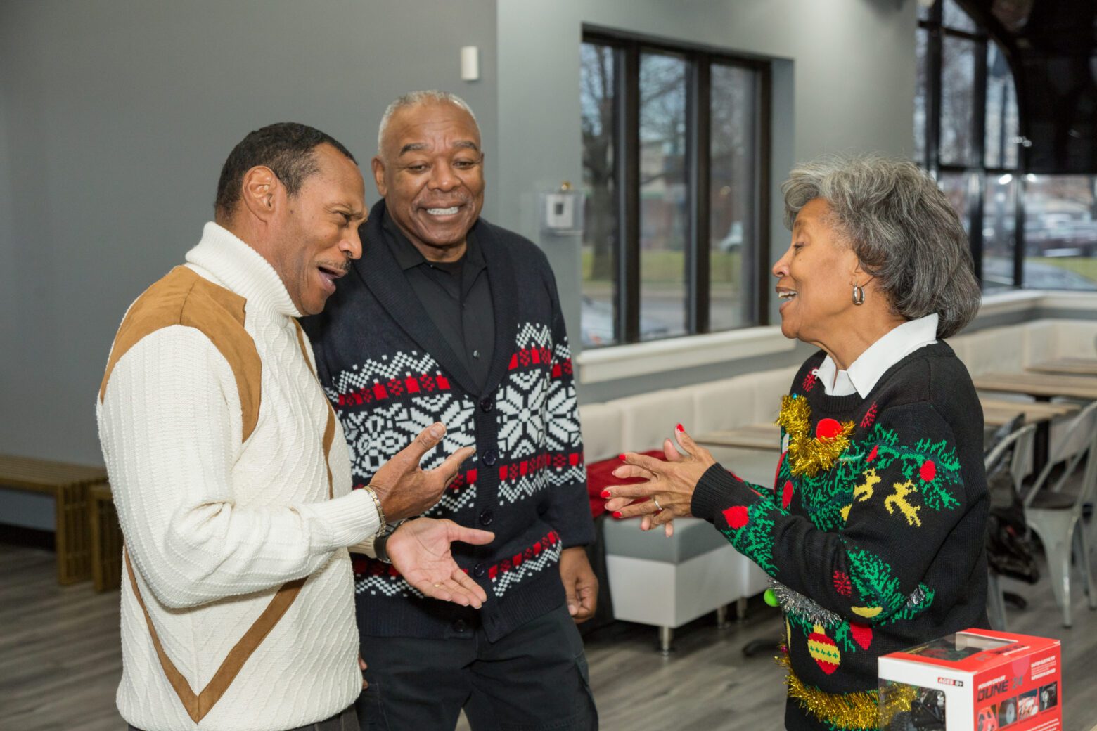 Three people sharing a joyful moment indoors during the holidays.