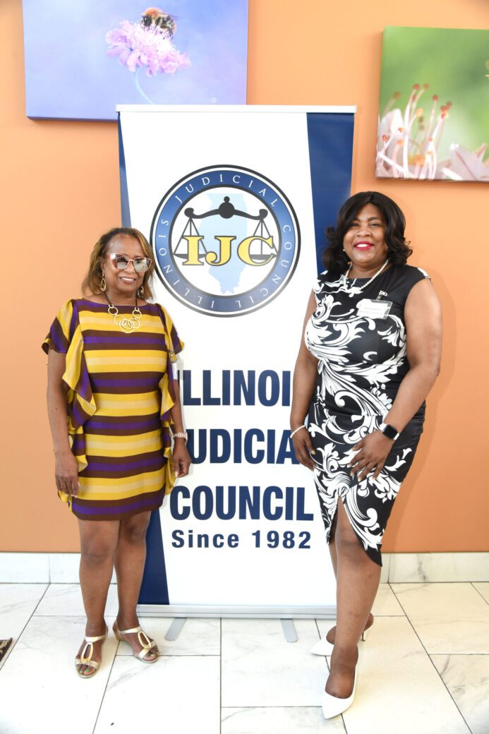 Two women posing in front of an Illinois Judiciary Council logo.