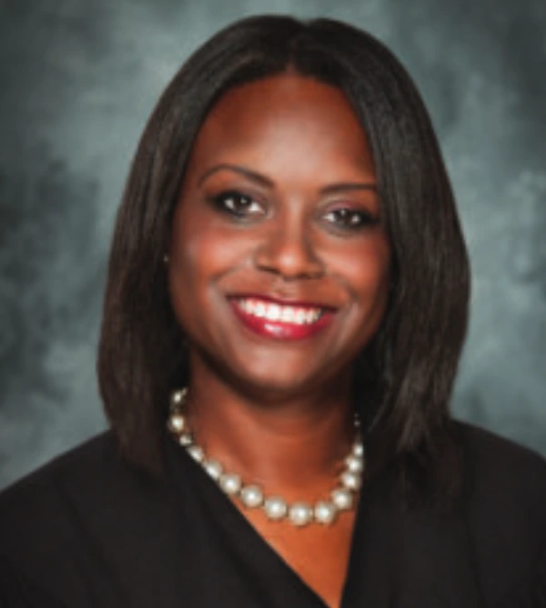 Professional portrait of a smiling woman with pearl necklace.