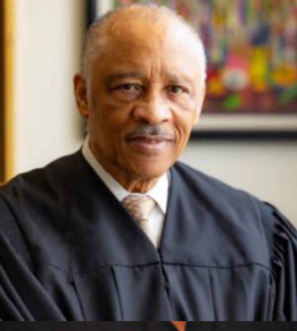 Portrait of a judge in black robes looking confidently at the camera.