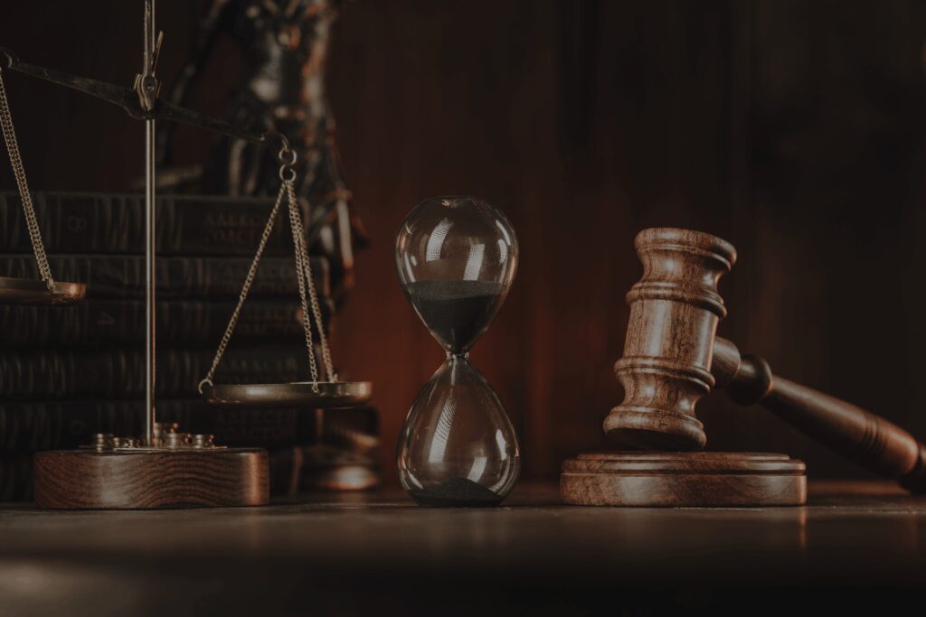 Legal symbols including hourglass, gavel, and scales of justice on a wooden surface.