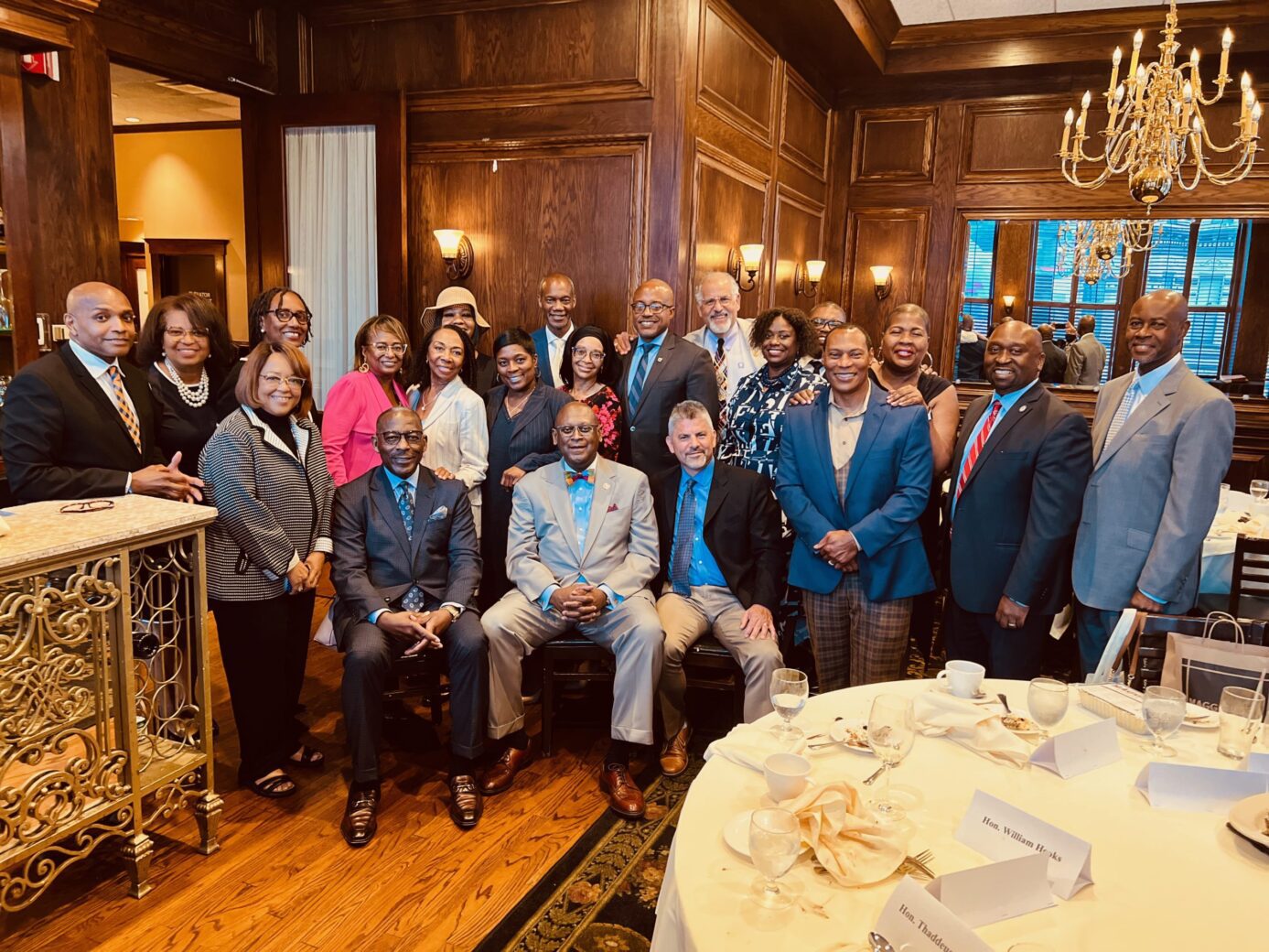 A diverse group of people posing in a wood-paneled room.
