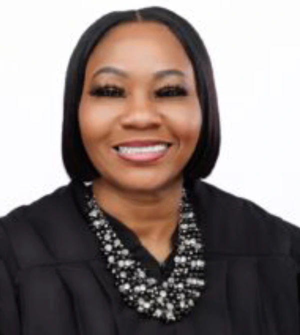 Smiling woman wearing a black blazer and patterned top.