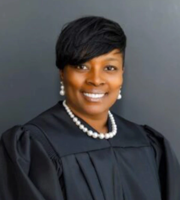 Portrait of a smiling woman in black judicial robe and pearl necklace.