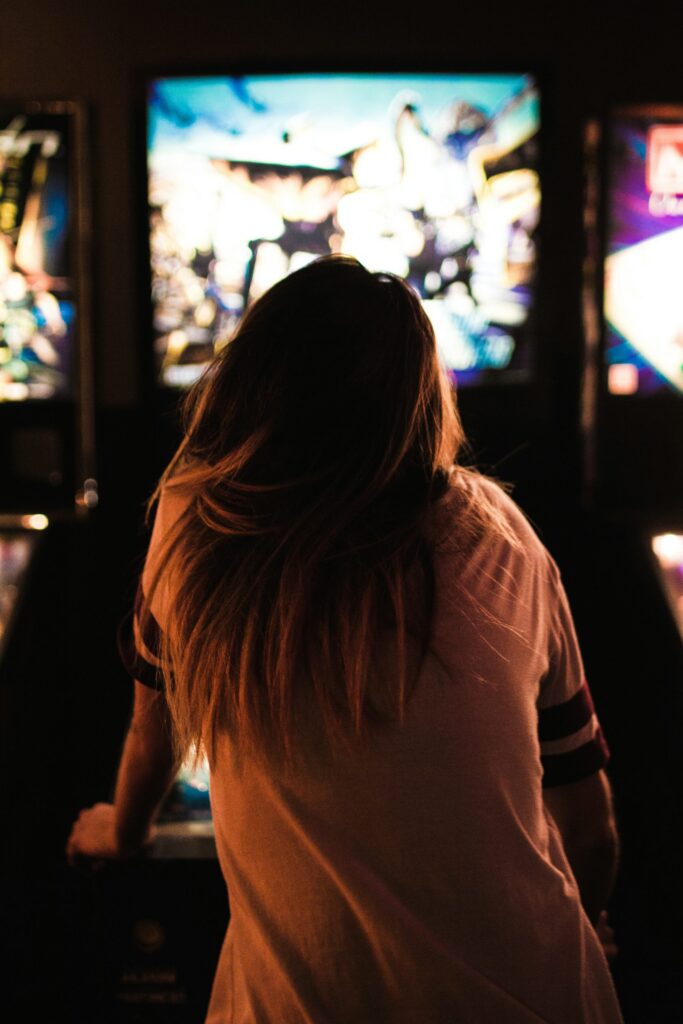 A person with long hair sitting indoors near stained glass windows.