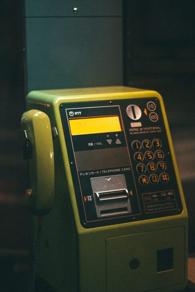 A vintage green public payphone with buttons and a coin slot.