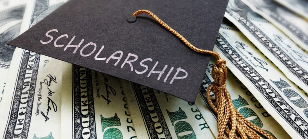 Graduation cap with 'Scholarship' text on dollar bills.