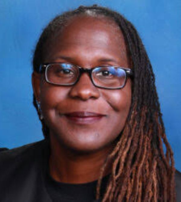 Portrait of a smiling woman with glasses and long braids.