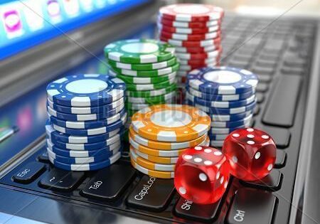 Colorful poker chips and red dice on a laptop keyboard.