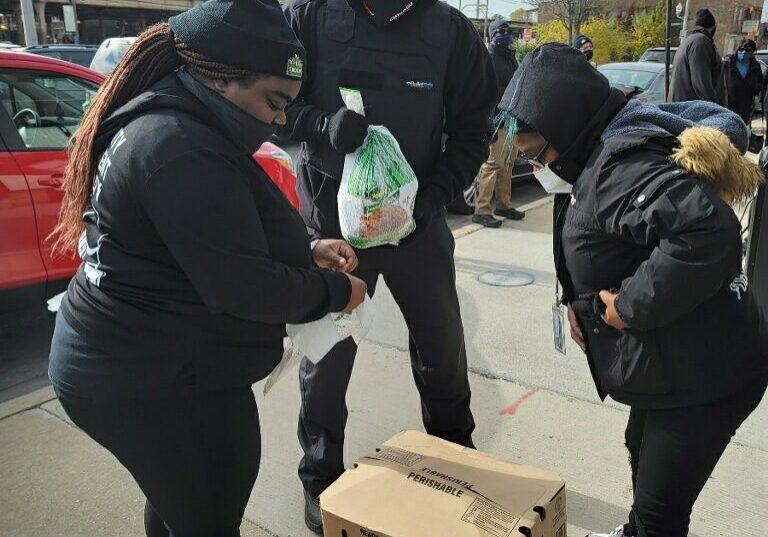 People distributing food outdoors on a cold day.