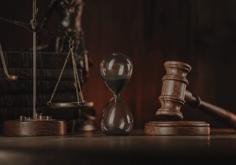 Legal symbols including hourglass, gavel, and scales of justice on a wooden surface.