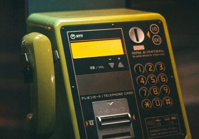 A vintage green public payphone with buttons and a coin slot.
