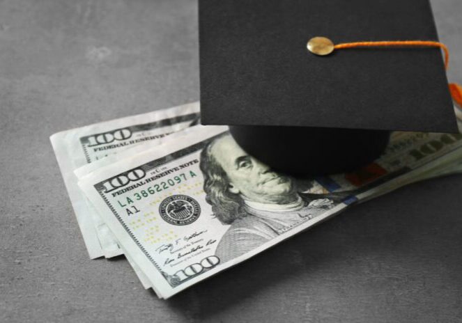 Graduation cap on hundred-dollar bills symbolizing financial success.