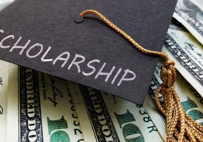 Graduation cap with 'Scholarship' text on dollar bills.